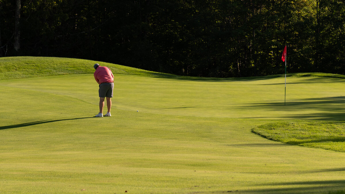 Male golfer putting on a green at Lake Winnipesaukee Golf Club.