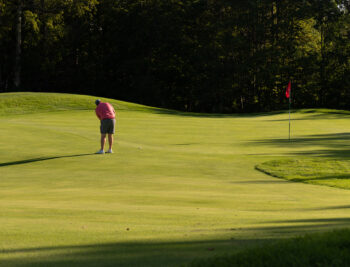 Male golfer putting on a green at Lake Winnipesaukee Golf Club.